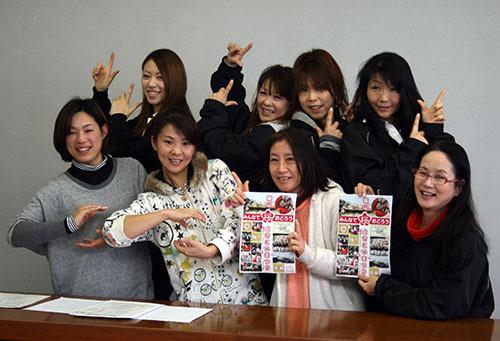 篠山よさこいまつり実行委員会の女性8名（前列はチラシを持っている方と手でおむすびの形を作っている方、後列は親指と人差し指を立て両手でポーズをとっている方）の写真